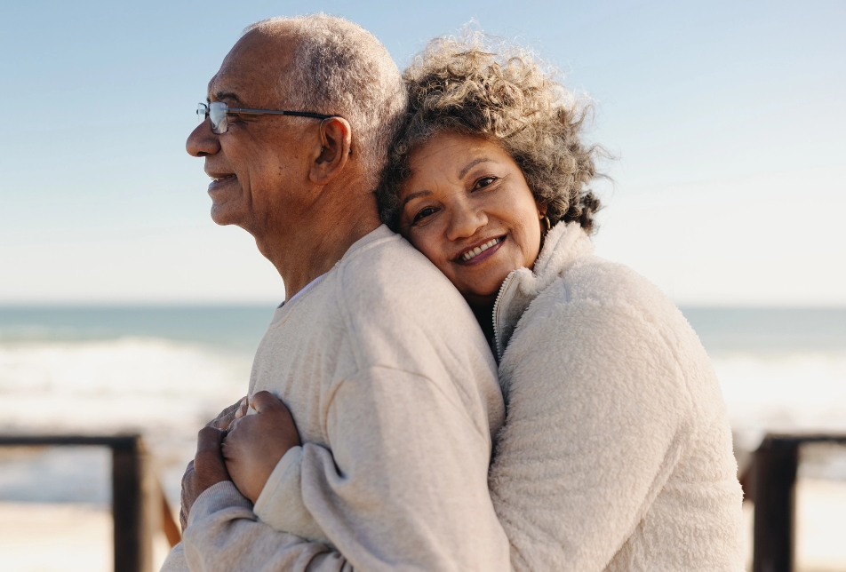 Aging Interventions - Spouse adult care. An older couple is hugging at the beach